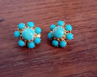 May include: A pair of gold tone clip-on earrings with turquoise stones. Each earring features a central turquoise stone surrounded by smaller turquoise stones.