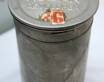 May include: A silver metal container with a lid labeled "Tank Kodak Developer". The lid has a red and white sticker with the number "16" on it.
