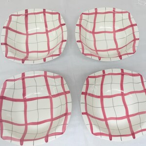 May include: Set of four white ceramic bowls with a pink and grey checkered pattern.