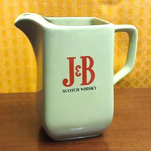 May include: A set of three ceramic mugs with a speckled, matte finish. The mugs are in shades of cream, light brown, and dark brown. Each mug has a simple, minimalist design and a rounded handle.