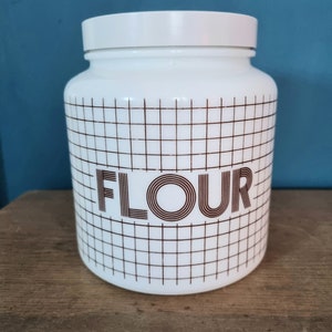 May include: White ceramic canister with a brown grid pattern and the word "FLOUR" in brown lettering.