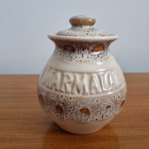 May include: A white ceramic jar with a brown lid and a brown glaze. The jar has the word "MARMALADE" embossed on the front.