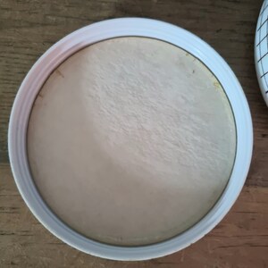 May include: White round lid with a smooth, slightly textured surface. The lid is made of plastic and has a raised edge.