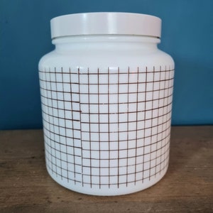 May include: White ceramic jar with a brown grid pattern. The jar has a white lid.