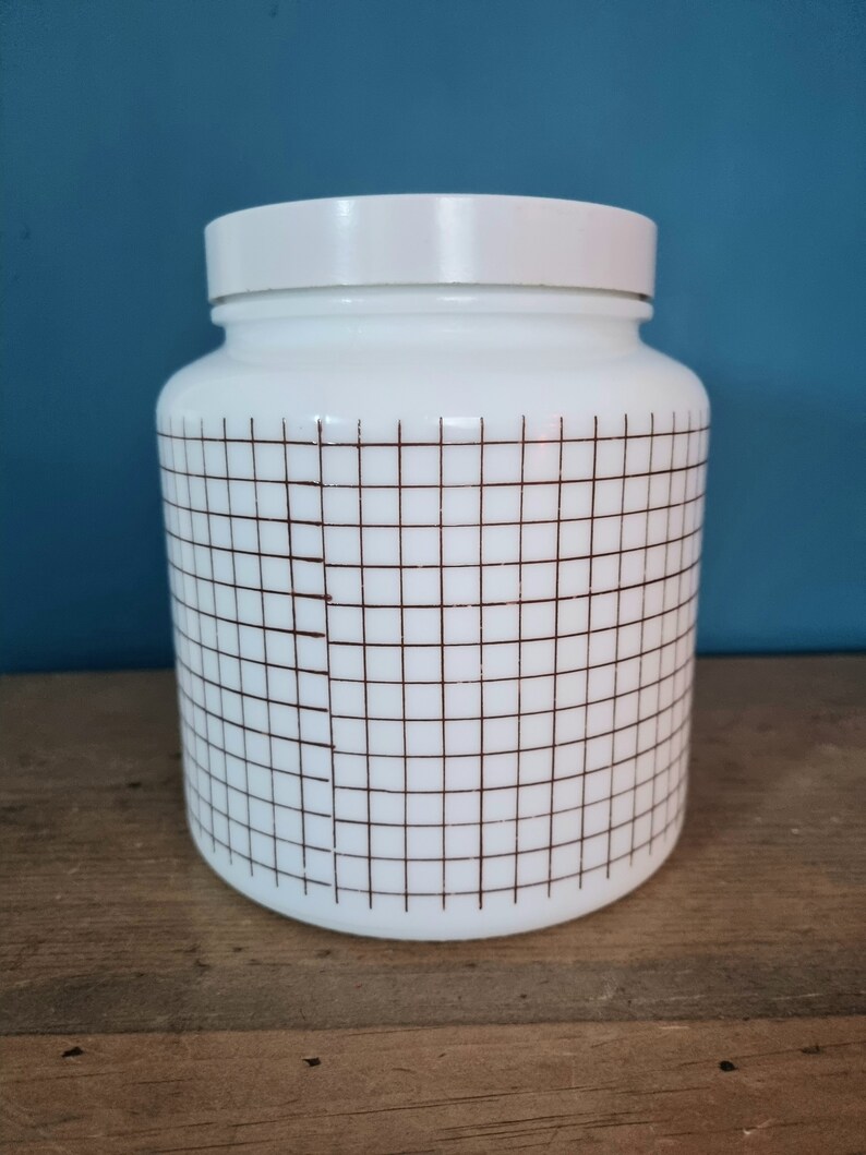 May include: White ceramic jar with a brown grid pattern. The jar has a white lid.