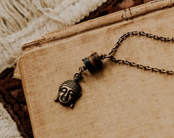 petite buddha. a simple earthy buddha charm necklace adorned with earthy shell beads.