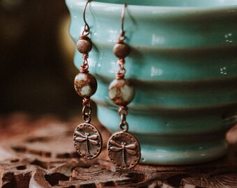 metamorphosis. a pair of copper dragonfly earrings adorned with earthy beads.