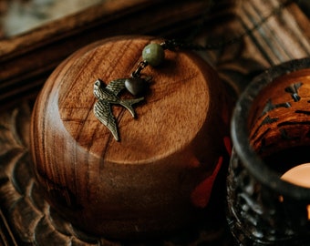 loves flight. a simple boho necklace with a bronze sparrow bird adorned with a copper heart and green glass bead.