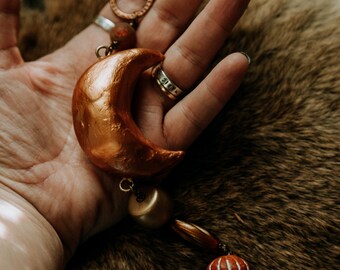 samarah. a hand formed clay moon adorned with earthy beads and a crystal suncatcher.