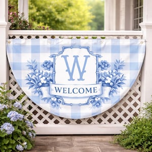 May include: A blue and white gingham welcome banner with a floral design and the letter "W". The banner has a semi-circular shape and is hanging on a white fence. The word "WELCOME" is written on a banner.