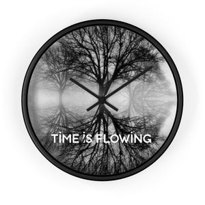 Op de afbeelding: Zwart-witte wandklok met een boom silhouet ontwerp. De klok heeft een spiegelbeeld van een boom en de tekst "TIME IS FLOWING" in het wit. De klok heeft zwarte wijzers en een zwarte rand.