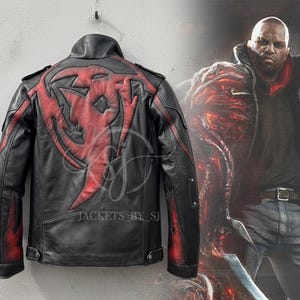 Puede incluir: Chaqueta de cuero negra con detalles rojos y un diseño estilizado en la espalda. La chaqueta tiene cuello alto y cierre de cremallera. La imagen también muestra a una persona con una chaqueta similar.