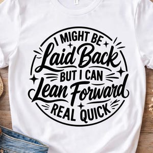 Könnte beinhalten: Ein weißes kurzärmeliges T-Shirt mit schwarzem Text in einem kreisförmigen Design, das lautet, I MIGHT BE Laid Back BUT I CAN Lean Forward REAL QUICK, mit kleinen Sternakzenten um den Schriftzug auf der Vorderseite des Kleidungsstücks.