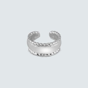 May include: A silver ear cuff with a rope-like texture on the top and bottom edges, and a smooth, flat center band. The open design allows it to be worn without piercing.