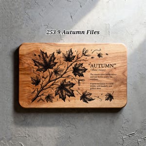 May include: A rectangular wooden cutting board featuring a black engraved illustration of maple leaves on a branch. The text reads: 253 9 Autumn Files, "AUTUMN" /ˈɔtəm/ (noun), The season when leaves dance and rain writes poetry on windows.