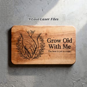 以下が含まれることがあります： 丸みを帯びた角を持つ木製のまな板で、「Grow Old With Me」と「The best is yet to come」というフレーズが刻まれています。デザインには、花のリースに囲まれた手を組んだ様子が含まれています。「9 Love Laser Files」というテキストが上部にあります。