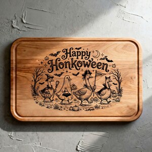 May include: A rectangular wooden cutting board featuring a laser-engraved illustration of four geese in Halloween costumes. The text reads Happy Honkoween, accompanied by bats, trees, and pumpkins. The board has rounded corners and a grooved edge.