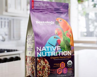 May include: A bag of Beakology Native Nutrition organic parrot food. The bag is purple and features colorful parrot illustrations. The text on the bag includes "Certified Avian Specialist Formulated" and "Organic Parrot Food". The net weight is 2 lbs.