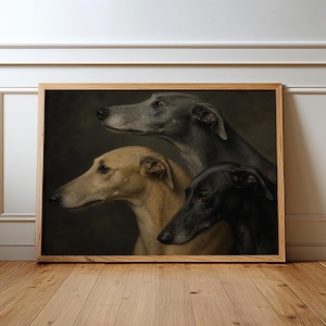 May include: A framed print featuring three greyhound dogs in profile. The dogs are depicted in shades of grey, tan, and black against a dark background. The artwork is displayed in a wooden frame, leaning against a white wall and wooden floor.