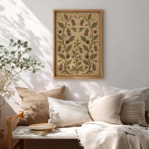 May include: A rectangular framed wall art piece featuring a symmetrical botanical illustration of purple bell-shaped flowers and green leaves on a textured beige background, enclosed in a light-toned wooden frame hanging on a plain wall.