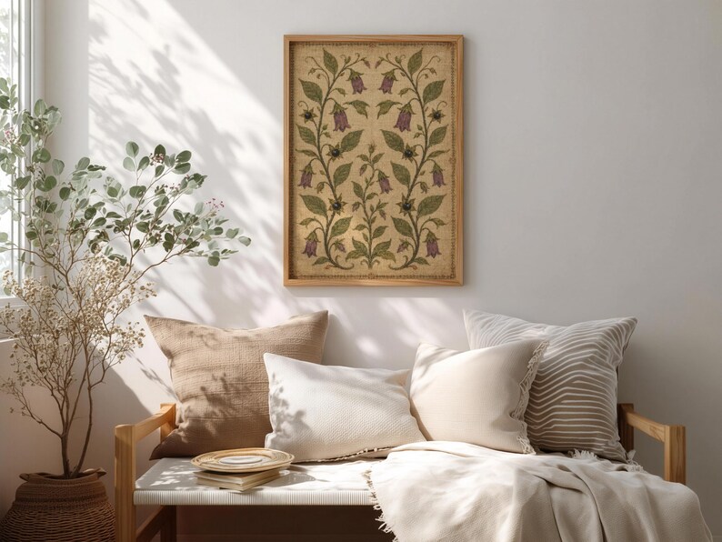 May include: A rectangular framed wall art piece featuring a symmetrical botanical illustration of purple bell-shaped flowers and green leaves on a textured beige background, enclosed in a light-toned wooden frame hanging on a plain wall.