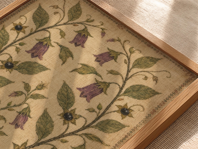 May include: A framed rectangular wall art piece featuring a beige linen-textured background with a botanical illustration of trailing green vines, dark green leaves, small black berries, and purple bell-shaped flowers encased in a light wood frame.