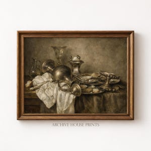 May include: A framed still life print featuring a collection of antique silver serving pieces, glassware, and plates of food. The artwork has a warm, sepia-toned color palette and is set against a dark background. The text "ARCHIVE HOUSE PRINTS" is at the bottom.