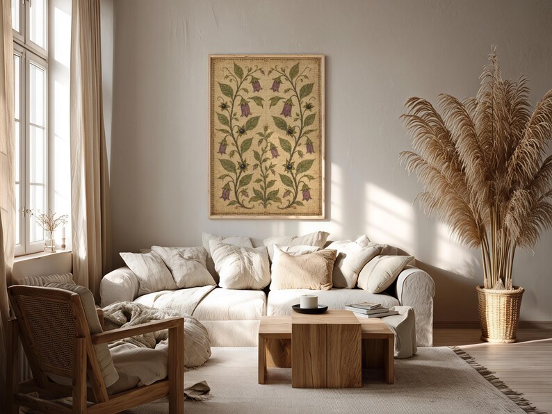 May include: A rectangular wall art print featuring a symmetrical botanical illustration of purple bell-shaped flowers and green leaves on a textured beige background, enclosed in a simple light-colored wooden frame hanging on a plain wall.