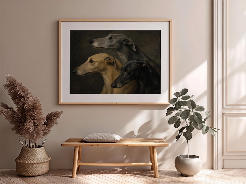 May include: Framed art print featuring three greyhounds in profile. The dogs are depicted in shades of grey, tan, and black against a dark background. The artwork is displayed in a light wood frame, adding a touch of elegance to the room.