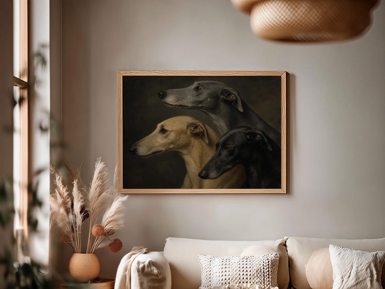 May include: A framed print featuring three greyhounds in profile. The dogs are depicted in shades of grey, tan, and black against a dark background. The artwork is displayed in a light-colored wooden frame, adding a touch of elegance to the room.