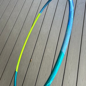 Puede incluir: Un aro de hula azul, verde y amarillo con un acabado metálico.