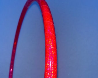 Può includere: Un cerchio rosso con glitter iridescente. Il cerchio è fatto di plastica e ha un diametro di circa 91 cm.