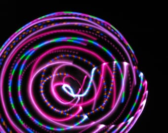 May include: A swirling pattern of pink, blue, green, and orange lights creates a colorful abstract design against a black background.