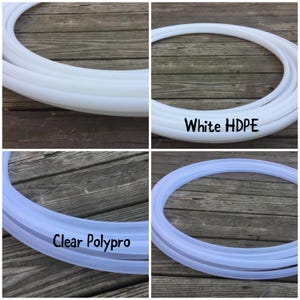 May include: Two hoop dance hoops, one white HDPE and one clear Polypro, are shown on a wooden surface.