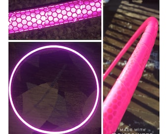 Può includere: Un cerchio da ginnastica rosa con un motivo a nido d'ape riflettente. Il cerchio è in plastica e ha un diametro di circa 99 cm.