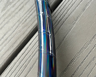 Può includere: Primo piano di un cerchio nero iridescente con una superficie lucida e riflettente. Il cerchio è realizzato in un materiale resistente e ha una finitura liscia e lucida.