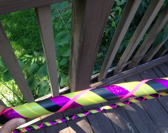 Könnte beinhalten: Ein gelber, schwarzer und pinkfarbener Hula-Hoop mit einem glitzernden pinkfarbenen Streifen.