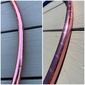 May include: Close-up of a rose gold hoop with a textured surface. The hoop is made of metal and has a shiny finish.