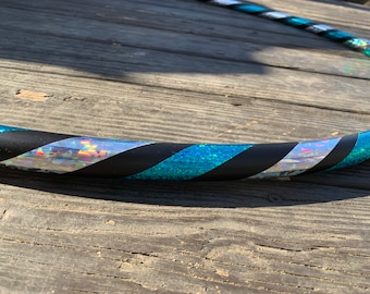 Könnte beinhalten: Ein schwarzer und türkisfarbener Reifen mit silbernem Glitzerband. Der Reifen ist aus Kunststoff und hat einen Durchmesser von etwa 76 cm.