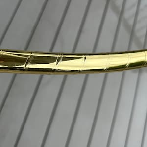 May include: Close-up of a gold-coloured hoop with a textured surface.