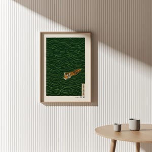May include: Framed art print featuring a tiger swimming in green water with a wave pattern. The tiger has orange and black stripes. The print is in a light brown frame and includes Japanese text.