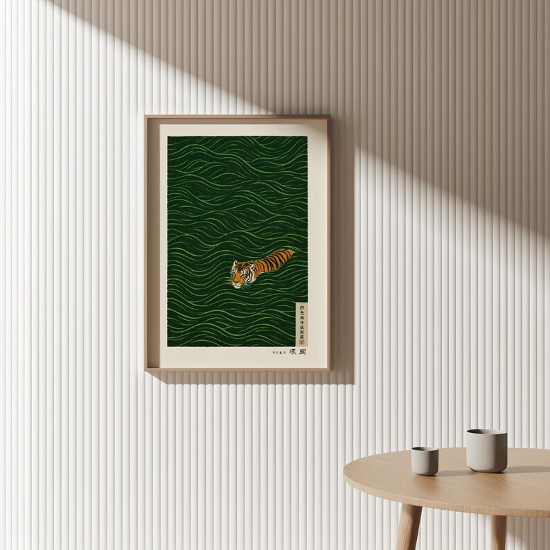 May include: Framed art print featuring a tiger swimming in green water with a wave pattern. The tiger has orange and black stripes. The print is in a light brown frame and includes Japanese text.