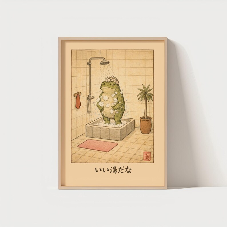 May include: A framed print featuring a green frog taking a shower in a stone tub. The frog wears a shower cap and is surrounded by bubbles. The bathroom has a shower head, a towel, a small rug, and a potted plant. The Japanese text "いい湯だな" is at the bottom.