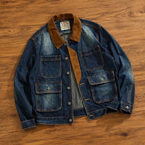 May include: A blue denim jacket with a brown corduroy collar and four front pockets. The jacket has a button-up closure and a label on the collar. The jacket is laid on a wooden surface.