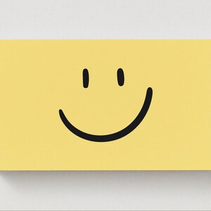 May include: A yellow rectangular canvas featuring a black smiley face. The face has two vertical black lines for eyes and a curved black line for a mouth. The canvas is set against a white background.