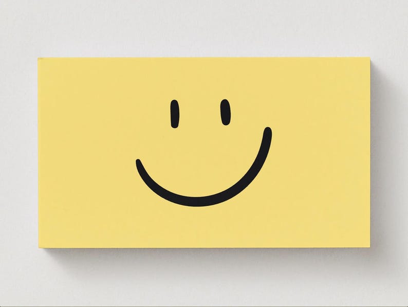 May include: A yellow rectangular canvas featuring a black smiley face. The face has two vertical black lines for eyes and a curved black line for a mouth. The canvas is set against a white background.