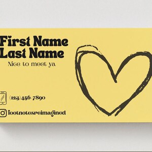 May include: A yellow business card with black text and a black heart illustration. The card includes the text "First Name Last Name", "Nice to meet ya", a phone number, and an Instagram handle.