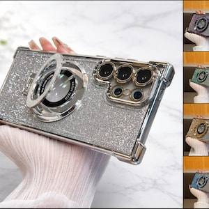 May include: A silver glitter phone case with a camera lens design. The case has a ring holder and a clear bumper. The image shows the case in a hand, with additional color options displayed on the right.
