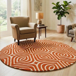 May include: A round area rug featuring a repeating geometric pattern in burnt orange and cream. The design consists of concentric rounded square shapes with a central almond-like motif, creating a textured look on the floor surface.