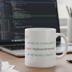 May include: White ceramic mug with a handle, featuring programming code in various colors. The text reads: "Life is beautiful" and "Reality check". A laptop and pen are in the background.